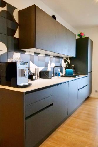 une cuisine avec des armoires noires et un comptoir dans l'établissement Chambre D'hôtes sur Île de Nantes, à Nantes