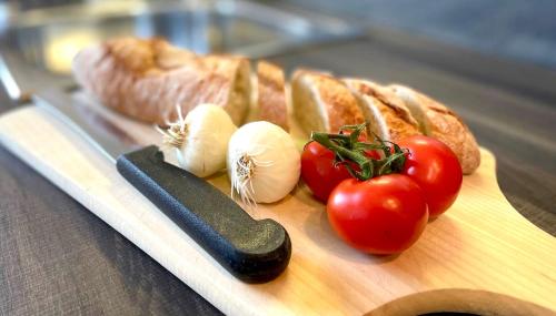 a cutting board with tomatoes and a knife and bread at Ferienhaus Jäger in Friedrichshafen
