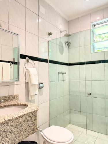 a bathroom with a shower and a toilet and a sink at Ilha Porchat Hotel in São Vicente