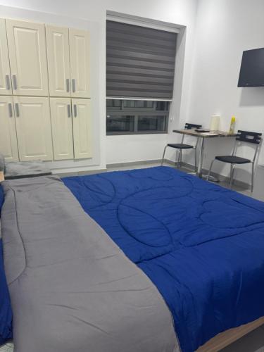 a bedroom with a blue bed with two chairs at Studio Résidence Prestige in Mahdia