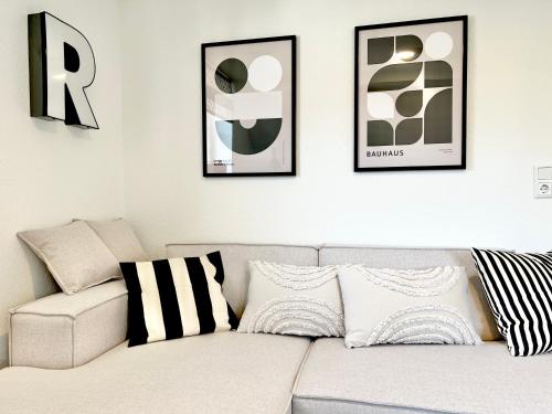 a living room with a white couch and three framed pictures at Neu MAKERS and ROOMS APARTMENTS Rosental am Schlosspark Detmold in Detmold