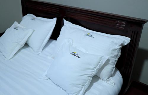 a bed with four white pillows on it at ViRRA Suites in Mbarara