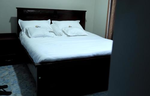 a bed with white sheets and pillows in a room at ViRRA Suites in Mbarara