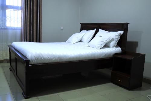 a bedroom with a bed with white sheets and pillows at ViRRA Suites in Mbarara