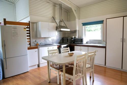 a kitchen with a table and chairs and a refrigerator at The Hopeful Hut-Cosy beach vibes-Bring the dog & boat in Kurrimine Beach