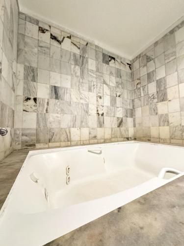 a white bath tub in a bathroom with tiles at Ilha Porchat Hotel in São Vicente