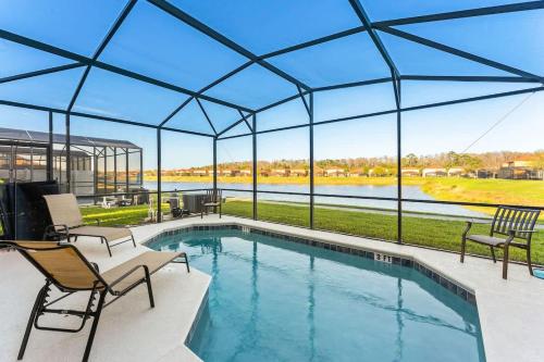 a swimming pool in a pavilion with two chairs and a patio at 4BR Townhome with Lake View – BL481 in Kissimmee