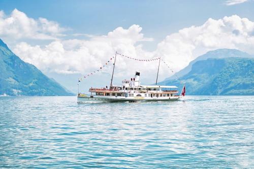 a boat on the water with mountains in the background at SOLUNA STAY I See & Berge I Luzern I Familienfreundlich I Ski I Self-check-in I Free Parking in Küssnacht