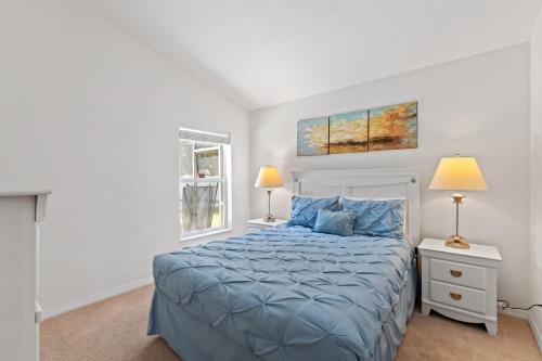 a bedroom with a bed with a blue comforter and two lamps at Ground floor spacious house 4BR VP2512 in Kissimmee