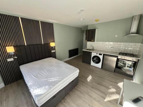 a small bedroom with a bed and a kitchen at The Dixon - Commonwealth Games 2026 in Glasgow