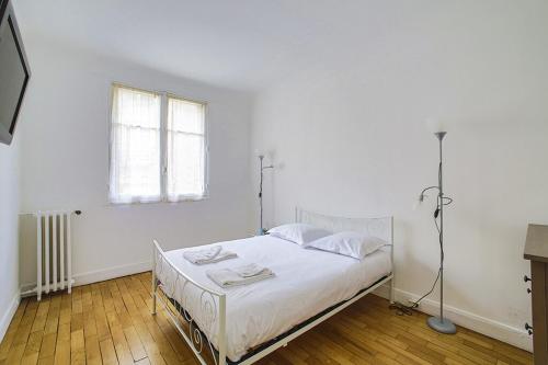 une chambre blanche avec un lit et une fenêtre dans l'établissement Le Breteuil Calme & Lumineux Invalides, à Paris