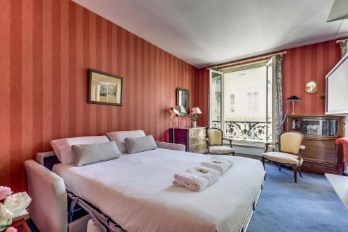 une chambre avec un grand lit aux murs rouges dans l'établissement Le Rubis de Paris élégant Notre-Dame & Panthéon, à Paris