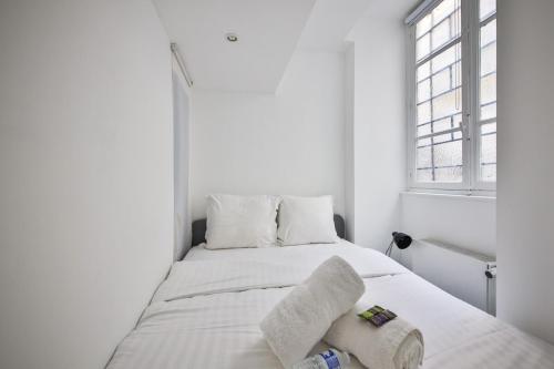 une chambre blanche avec un lit avec des serviettes dessus dans l'établissement Le Petit Rousseau - Cosy & Calme - Rivoli, à Paris