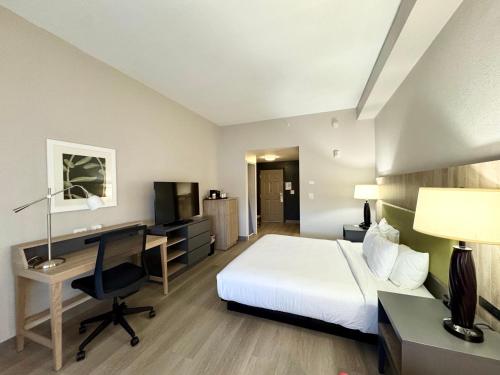 a hotel room with a bed and a desk with a computer at Country Inn & Suites by Radisson, Port Charlotte, FL in Port Charlotte