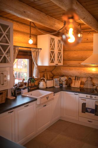 a kitchen with white cabinets and a sink at Forest Chalet with Jacuzzi and sauna, 4 km from Starý Smokovec in Nová Lesná