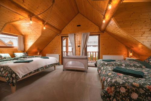 a bedroom with two beds in a wooden house at Forest Chalet with Jacuzzi and sauna, 4 km from Starý Smokovec in Nová Lesná