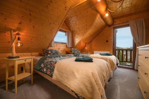 two beds in a room with a desk and windows at Forest Chalet with Jacuzzi and sauna, 4 km from Starý Smokovec in Nová Lesná
