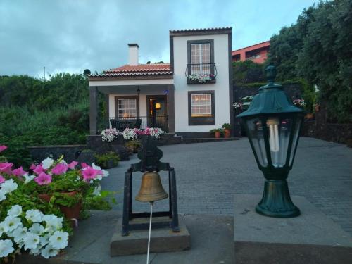 a small house with a street light and flowers at Casa Belcanto da Fajã in Feteira