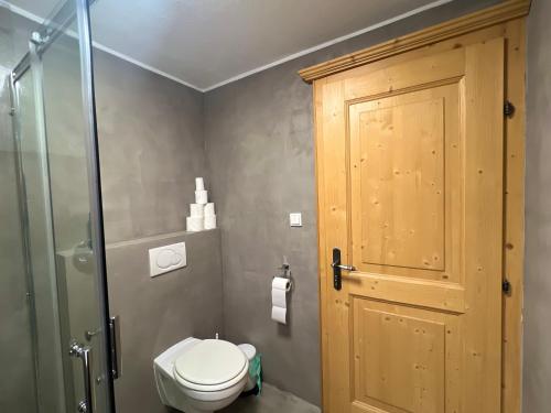 a bathroom with a toilet and a wooden door at Chalet Aurach in Aurach bei Kitzbuhel