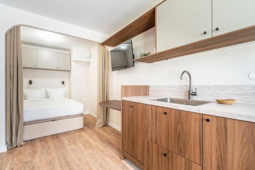 - une cuisine avec évier et un lit dans une chambre dans l'établissement Studio Cozy Design - Batignolles, à Paris