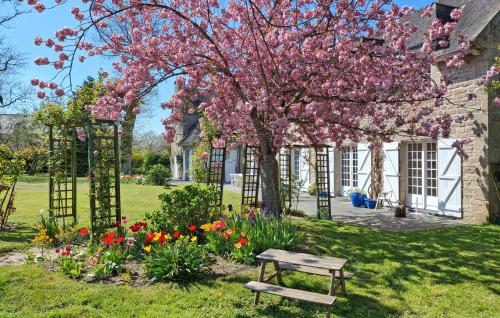 a bench in front of a house with a flowering tree at Gorgeous Home In Plélan-Le-Petit in Plélan-le-Petit