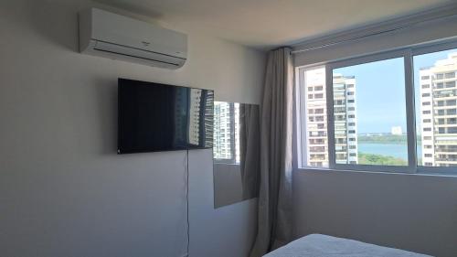 a bedroom with a tv and a window with a view at Ilha Pura Barra in Rio de Janeiro