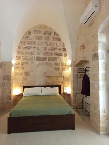 Un dormitorio con una cama en una pared de piedra. en Casa Ninì, en Maruggio