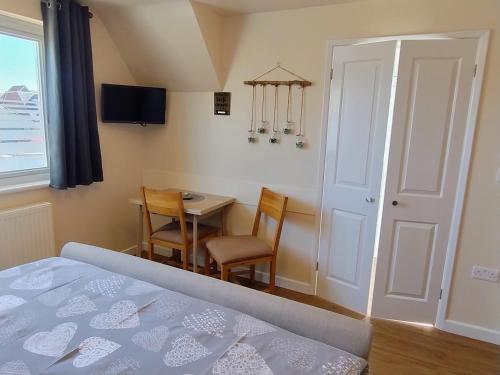 a bedroom with a bed and a table and a chair at Little Bassett Bed & Breakfast in Totland