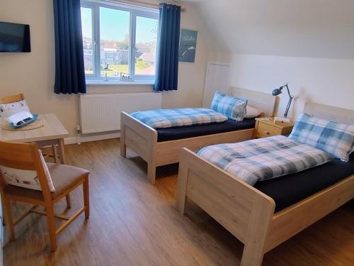 a room with two beds and a table and a window at Little Bassett Bed & Breakfast in Totland