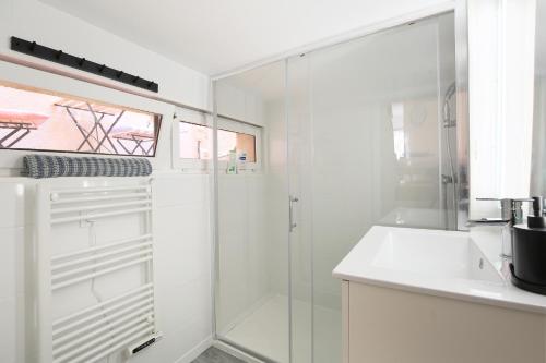 une salle de bain blanche avec une douche et un lavabo dans l'établissement Ô Loft climatisé d'Ony, à Toulouse