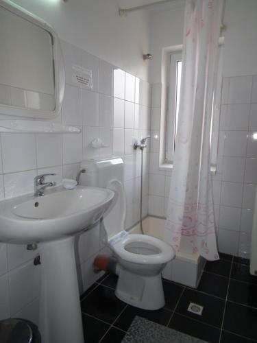 a white bathroom with a sink and a toilet at Pensiunea Ando in Bran
