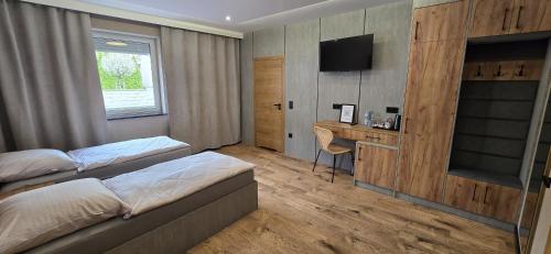 a bedroom with two beds and a desk and a television at KaMi Self check-in 24 h in Głogówek