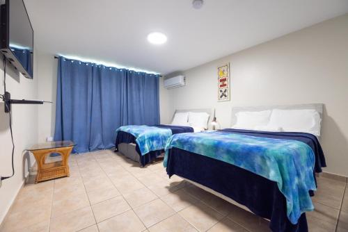 two beds in a room with blue curtains at Golden Dream Villas 306/A in Isabela