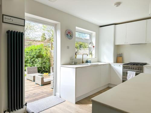 a kitchen with white cabinets and a large window at Modern 3 Bed Home - Pets Welcome - FREE Parking in Canterbury