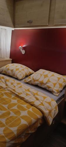 a bed with a yellow and white comforter in a bedroom at Hiška La Vita Kamp Terme 3000 Moravske Toplice vključeno 3x KOLO Športni rekviziti, Igrače in Moravske Toplice