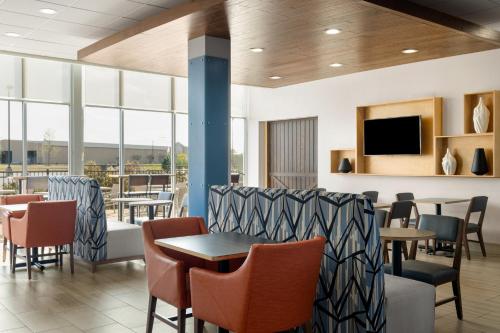 a restaurant with tables and chairs and a tv at Holiday Inn Express & Suites West Memphis by IHG in West Memphis