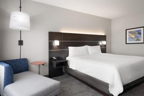 a hotel room with a bed and a chair at Holiday Inn Express & Suites West Memphis by IHG in West Memphis