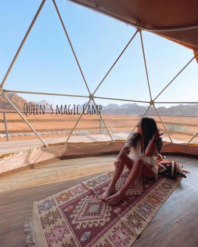 a girl sitting on a rug in a tent looking out at the desert at Queen's Magic Camp in Wadi Rum