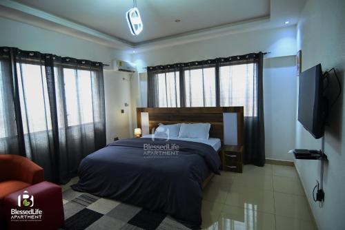 a bedroom with a bed and a tv and some windows at Frimpong Home - Blessed life Apartment in Kumasi