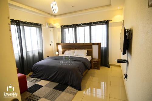 a bedroom with a bed in a room with windows at Frimpong Home - Blessed life Apartment in Kumasi