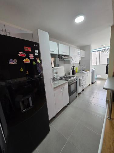Una cocina con refrigerador negro y gabinetes blancos. en Minidepartamento en Ñaña, en Chosica