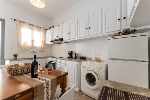 a kitchen with white cabinets and a table with a bottle of wine at Family Home Naxos in Naxos Chora