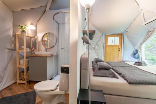 a bedroom with a bed and a toilet in a room at Glamping, Hot Tub & Projector by Nidumm Stay in Maribor