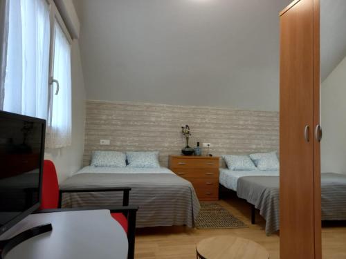 1 dormitorio con 2 camas, vestidor y TV en Casa "O Forte" en la playa, Espectacular ubicación, en Cangas de Morrazo
