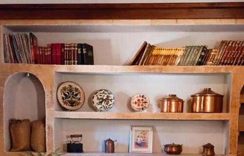 a shelf with dishes and books on it at Garden's House in Spáta