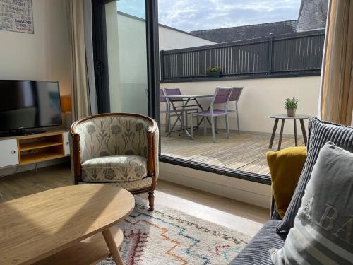 a living room with a television and a balcony at Plein centre Auray - Grand duplex 2 chambres avec terrasse ensoleillée in Auray
