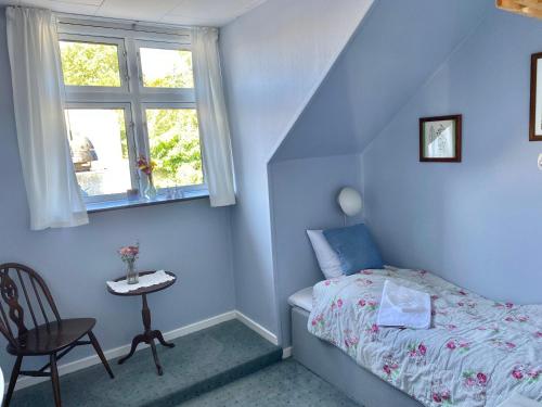 a bedroom with a bed and a table and a window at Gershøj Kro & Strand Hotel in Kirke-Hyllinge