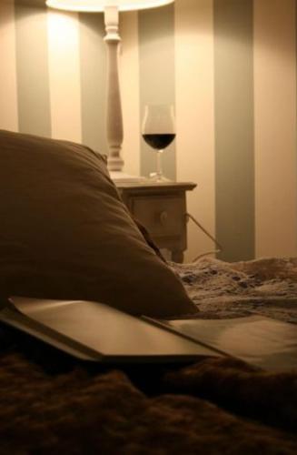a bed with a pillow and a glass of wine at Apartamentos Alcoba de Baco in Barbastro