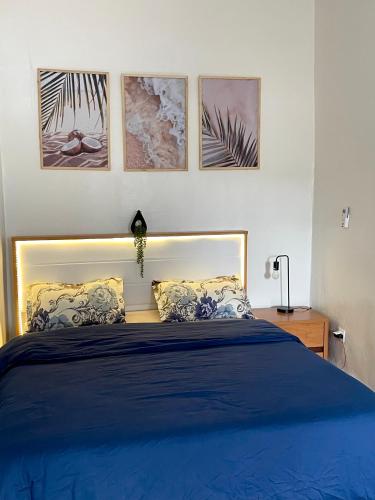 a bedroom with a blue bed with four pictures on the wall at Casamigos Cosy one bedroom appartment in Dakar