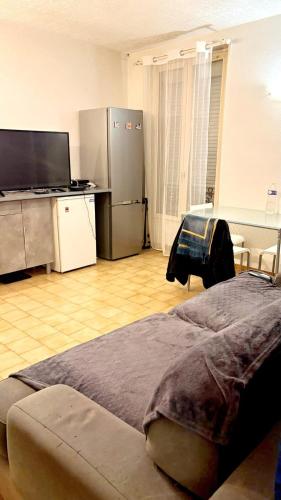 Cette chambre comprend un lit et un bureau avec un réfrigérateur. dans l'établissement Charmant appartement à Puteaux, à Puteaux